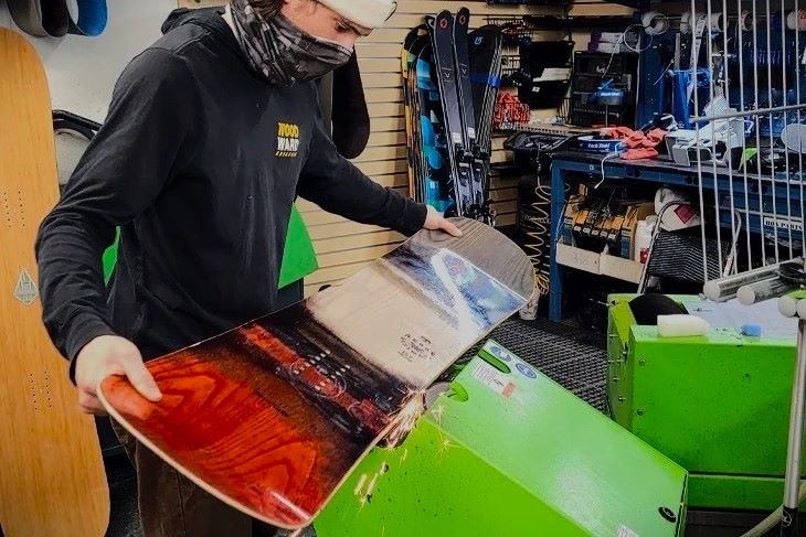 An Outdoor Expert from Sun & Ski Sports taking care of a customer's snowboard